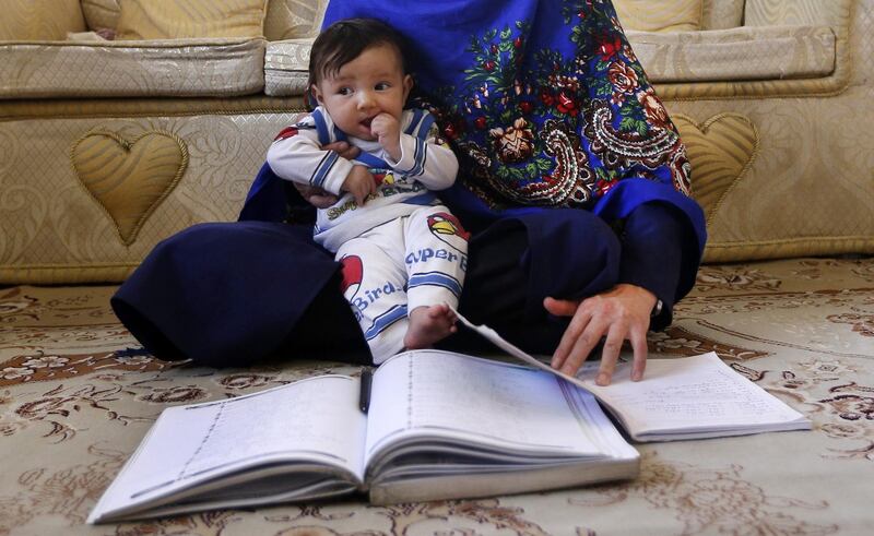 epa06639994 Afghan mother Jahantab Ahmadi, 25, holds her youngest child, three-month-old Khezran, while reading a book at a house in Kabul, Afghanistan, 31 March 2018 (issued 01 April 2018). Jahantab Ahmadi became a viral sensation on the Afghan web after she was photographed nursing her infant daughter while taking her university entrance exam. According to the Ministry of Education, 39 percent of the 9.2 million students in the country are girls. However, three to five million children, mostly girls, are still unable to attend schools.  EPA/HEDAYATULLAH AMID