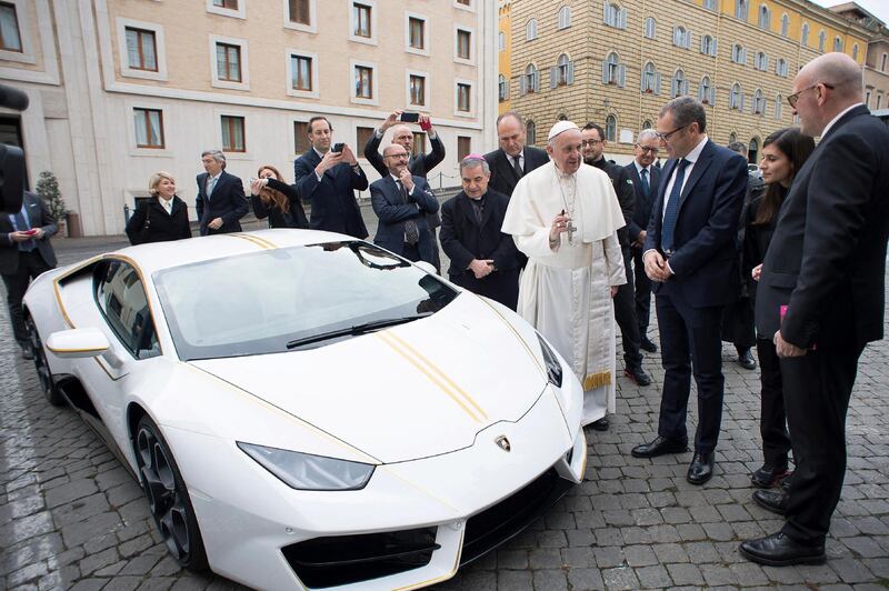 This handout photo taken on November 15, 2017 at the Vatican and released by the Vatican press office, Osservatore Romano shows Pope Francis speaking with Lambhorgini CEO Stefano Domenicali (2ndR) after receiving a Lamborghini Huracan as a gift from the Italian car company. (Photo by Handout / OSSERVATORE ROMANO / AFP)
