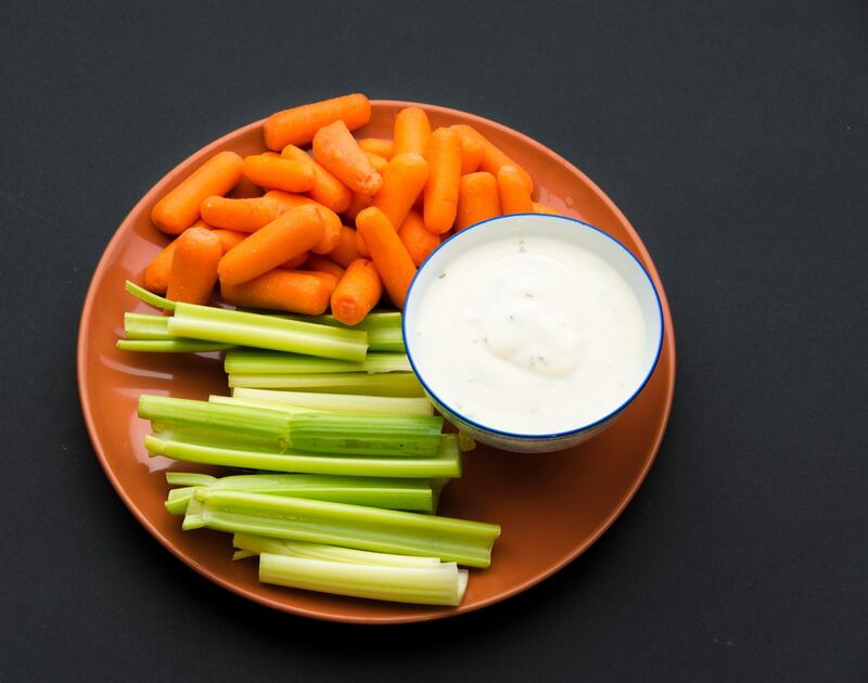 TORONTO, ONTARIO, CANADA - 2015/06/27: Baby carrots, celery sticks and a bowl full of delicious ranch sauce placed in a brown plate against a black background. (Photo by Roberto Machado Noa/LightRocket via Getty Images)