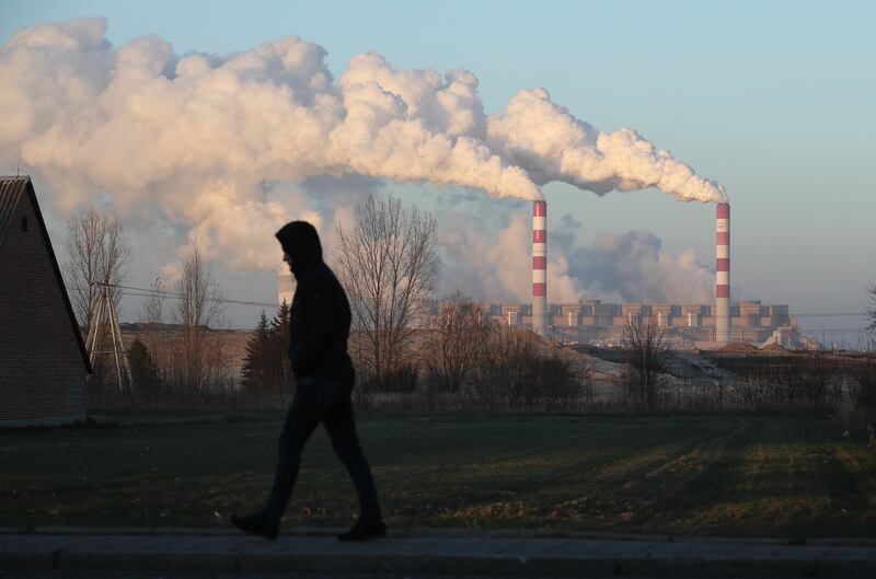 A man walks through the village of Kleszczow as steam and smoke rise from the Belchatow Power Station at Rogowiec, Poland. Getty Images