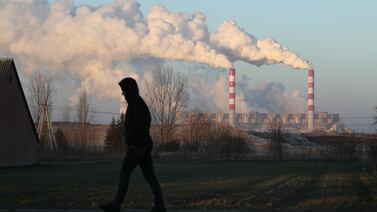 A man walks through the village of Kleszczow as steam and smoke rise from the Belchatow Power Station at Rogowiec, Poland. Getty Images
