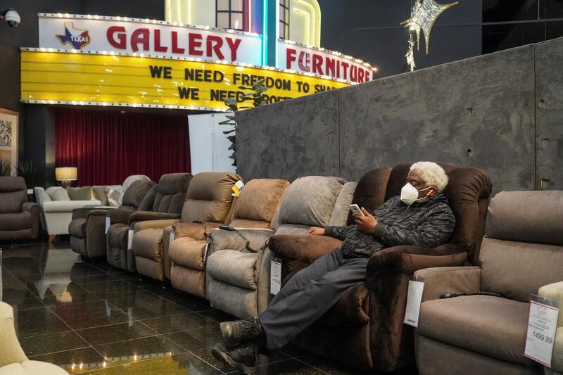 Alvin Williams, 66, checks on his smartphone while taking a shelter at Gallery Furniture store which opened its door and transformed into a warming station after winter weather caused electricity blackouts in Houston, Texas, U.S. February 17, 2021.  REUTERS/Go Nakamura