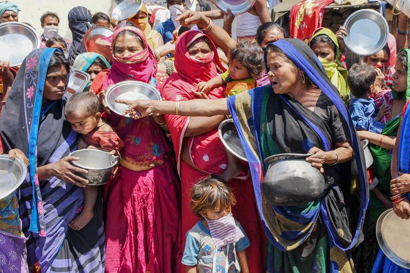 Migrant labourers and families from Bihar and Uttar Pradesh states hold kitchen utensils as they protest against the government for the lack of food at a slum area during a government-imposed nationwide lockdown as a preventive measure against the COVID-19 coronavirus, in Amritsar on April 22, 2020. (Photo by NARINDER NANU / AFP)