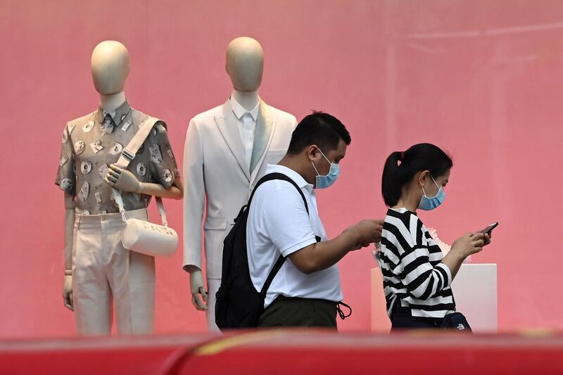 (FILES) In this file photo taken on June 18, 2020, a couple wearing face masks walk past a fashion retail outlet along the Orchard shopping belt in Singapore,  a day ahead of further easing of restrictions in Singapore due to the COVID-19 novel coronavirus.  Singapore plunged into recession in the second quarter as growth fell 41.2 percent quarter-on-quarter with the trade-dependent economy hammered by the coronavirus, preliminary data showed on July 14. / AFP / Roslan RAHMAN
