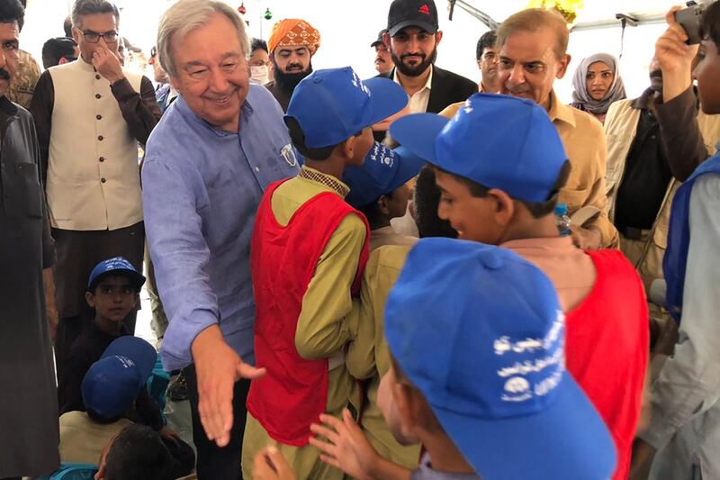 UN Secretary General Antonio Guterres, second left, and Pakistani Prime Minister Shahbaz Sharif, second right, meet children at a camp for people displaced by floods, in Usta Mohammad city, Balochistan province, on Saturday, September 10, 2022. AFP