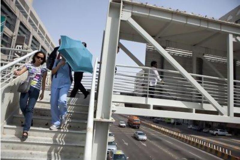 Pedestrians walk to and from the Abu Dhabi Mall on an overpass over the busy road in front of the mall. Authorities blocked off the street for use by pedestrians, forcing them to use the overpass instead of the risky jaywalking. Silvia Razgova / The National