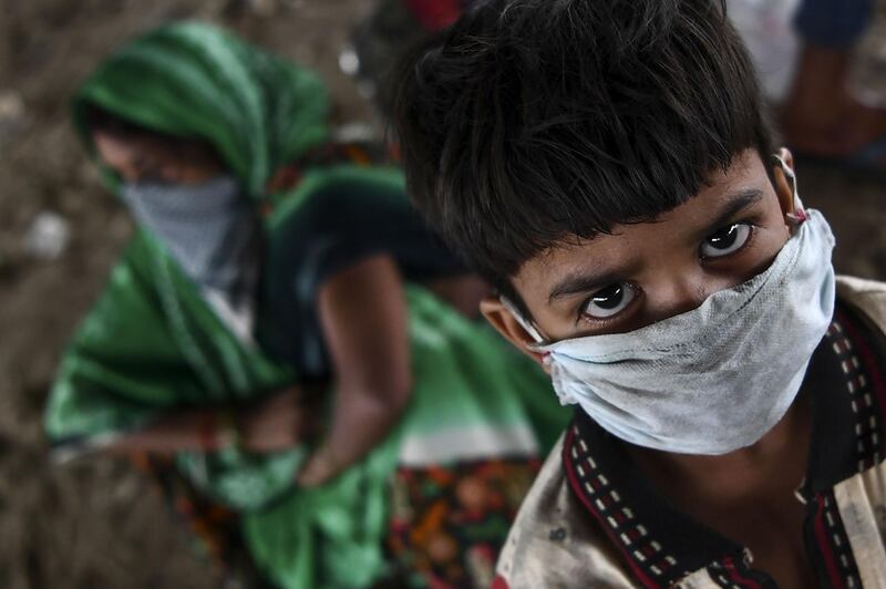 A young child from a migrant workers family waits for transport with others to return to their hometowns in Uttar Pradesh and Bihar states after police stopped them from crossing the Delhi-Uttar Pradesh border on foot as the government eased a nationwide lockdown as a preventive measure against the COVID-19 coronavirus, in New Delhi on May 17, 2020. / AFP / SAJJAD  HUSSAIN

