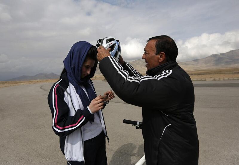 Coach Abdul Sadiqi assists Malika Yousufi with her helmet. Mohammad Ismail / Reuters