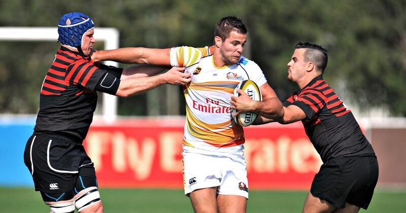 Abu Dhabi Saracens, in red, wrestle with a Dubai Hurricanes ball carrier in the Saracens' 21-18 win at The Sevens in Dubai City, Dubai on February 28, 2014. Jeff Topping for The National