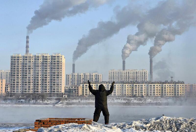 A man exercises in the morning as he faces chimneys emitting smoke behind buildings across the Songhua river in Jilin. Reuters