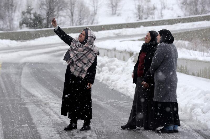 A woman takes a photograph with other women along a snow-covered road near the town of Bcharre in Mount Lebanon, north of the capital Beirut. AFP