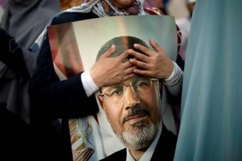 An Egyptian supporter of the Muslim Brotherhood holds a picture of deposed president Mohamed Morsi outside Cairo's Rabaa al-Adawiya mosque on July 5, 2013. Supporters of ousted Egyptian president Mohamed Morsi took to the streets in their tens of thousands, defying his army deposers and triggering running clashes that killed at least three people. AFP PHOTO/MAHMUD HAMS

 *** Local Caption *** 499088-01-08.jpg