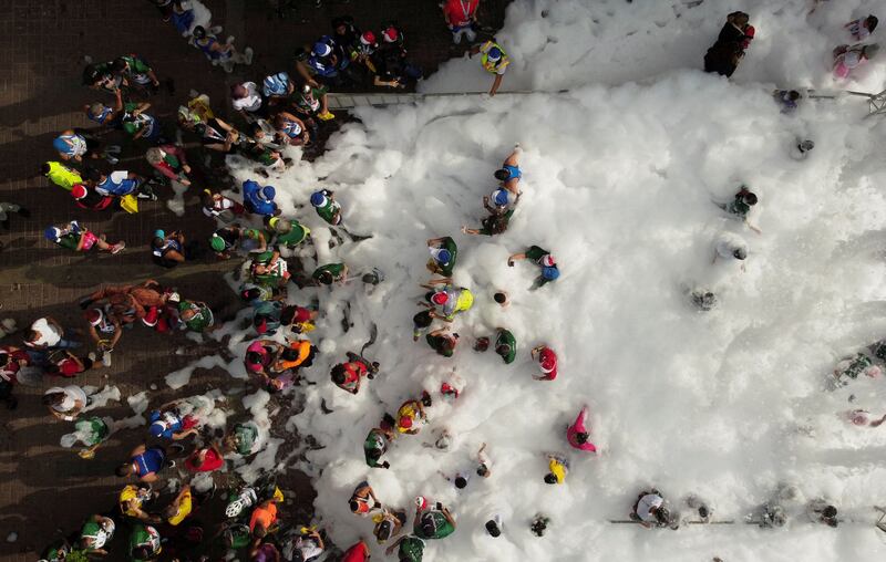 Runners, many wearing Christmas hats, play in foam at the end of Santa Run 10k race, in Caracas, Venezuela. Reuters