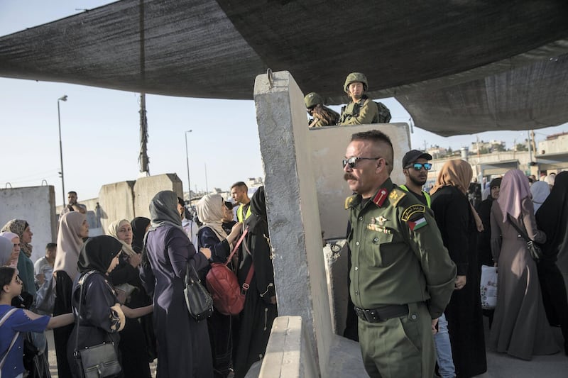 A Palestinian police man helps to direct women crossing the Qalandia checkpoint to cross to Jerusalem on May 17,2019. The Friday mornings during Ramadan is the most crowded foot traffic time at Qalandia, as tens of thousands of Palestinians from all around the West Bank cross through to pray in Jerusalem. This year, however, PA police were on the Palestinian side directing traffic, standing sometimes near to Israeli soldiers stationed behind concrete barriers. (Photo by Heidi Levine for The National).