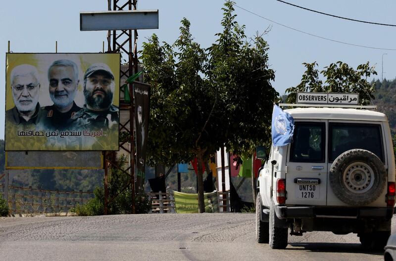 A UNIFIL patrol drives past a billboard showing the faces of slain (L ro R) Iraqi Hashed al-Shaabi (Popular Mobilisation) forces commander Abu Mahdi al-Muhandis, Iranian Quds Force commander Qasem Soleimani, and Hezbollah commander Imad Mughniyeh, in the southern Lebanese village of Adaisseh on the border with Israel on August 26, 2020. Israel said it had launched air strikes against Hezbollah observation posts in Lebanon after shots were fired from across the border towards its troops the previous evening. / AFP / Mahmoud ZAYYAT
