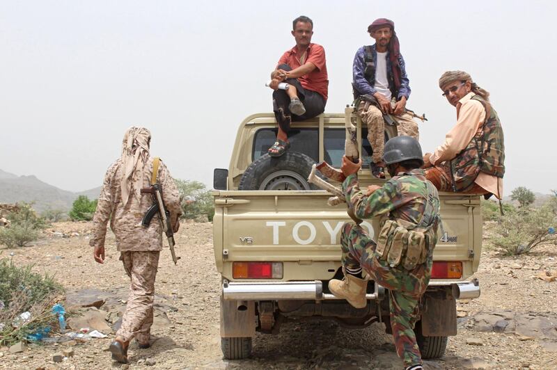 Yemeni pro-government fighters sit at the back of an armed pick-up truck.