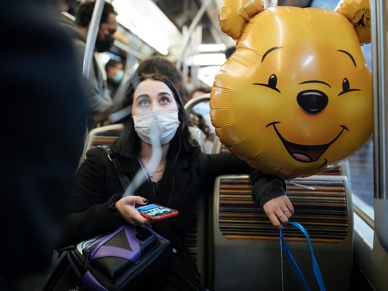 A masked woman holds a Winnie the Pooh inflatable balloon, inside the subway, in Paris. Some doctors expressed relief but business owners despaired as France prepared to shut down again for a month to try to put the brakes on the fast-moving virus. AP Photo