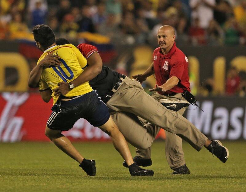 Security personnel catch a field intruder during a Copa America Centenario semifinal football match between Chile and Colombia in Chicago, Illinois, United States, on June 22, 2016. / AFP / Tasos Katopodis