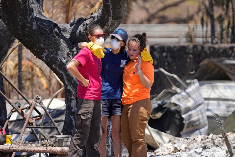 Women console each other after digging through the rubble of a home destroyed by the wildfire in Lahaina, Hawaii. AP