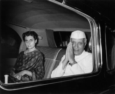 October 1961:  Indian prime minister Pandit Nehru (1889 - 1964) clasping his hands in salute while sitting with his daughter, Indira Gandhi, (born Indira Priyardarshini Nehru, 1917 - 1984) in the backseat of a car.  (Photo by Hulton Archive/Getty Images)