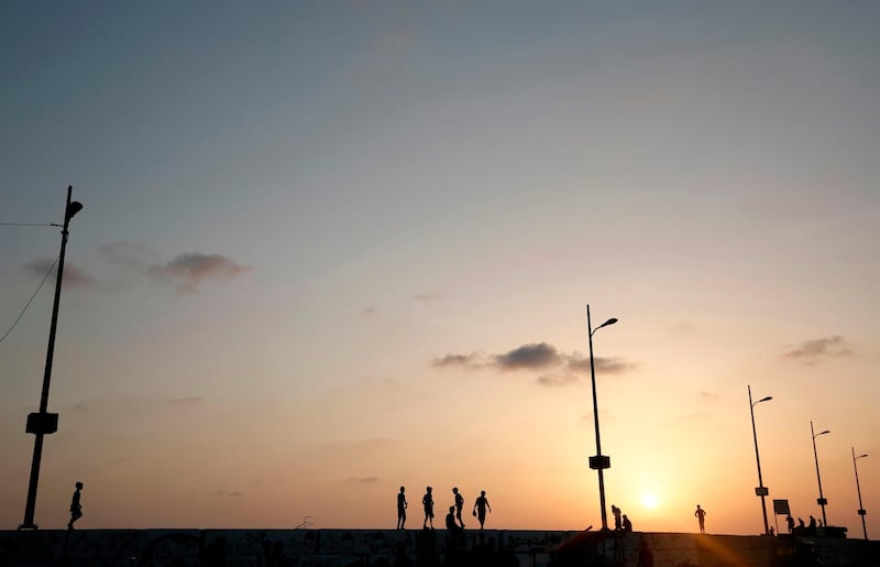 Palestinians walk by the sea at sunset in Gaza City. AFP