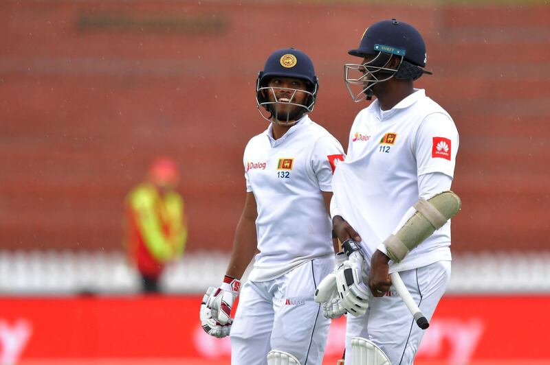 Sri Lanka's Kusal Mendis (L) and teammate Angelo Mathews walk from the field as rain starts to fall during day five of the first Test cricket match between New Zealand and Sri Lanka at the Basin Reserve in Wellington on December 19, 2018. / AFP / Marty MELVILLE
