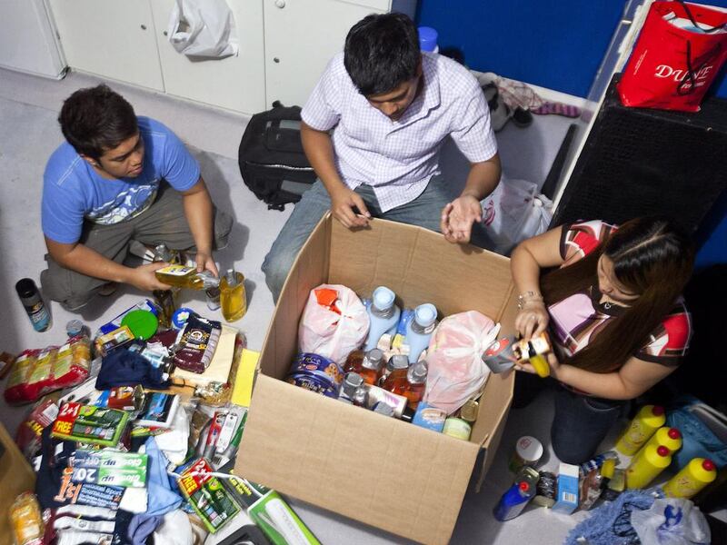 From left, Filipinos John Paul, Francis and Angel Laguilles prepare a ‘balikbayan’ care package for family members. Andrew Henderson / The National 
