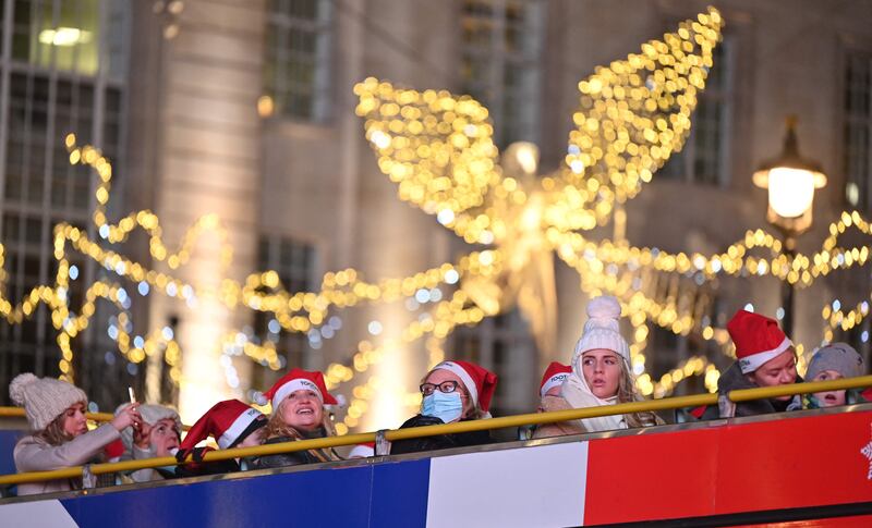 Passengers wearing Santa hats sit on the top deck of a tour bus as they view the Christmas lights in central London. AFP