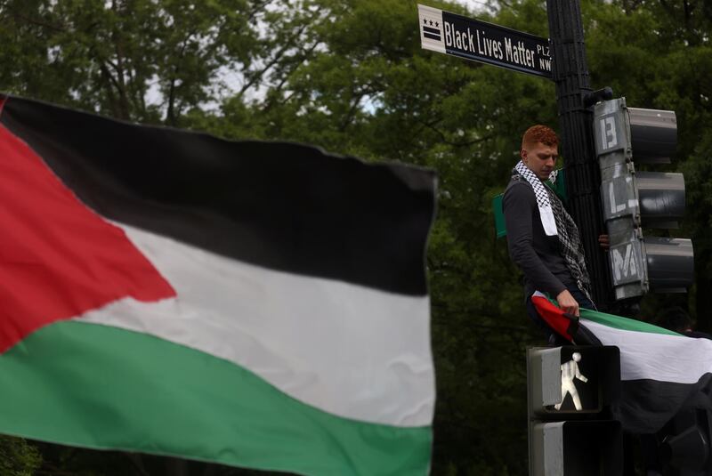 Moustafa Almeky stands on a street light as he joins fellow pro-Palestinian demonstrators outside the White House after marching from the US State Department building in Washington. Reuters
