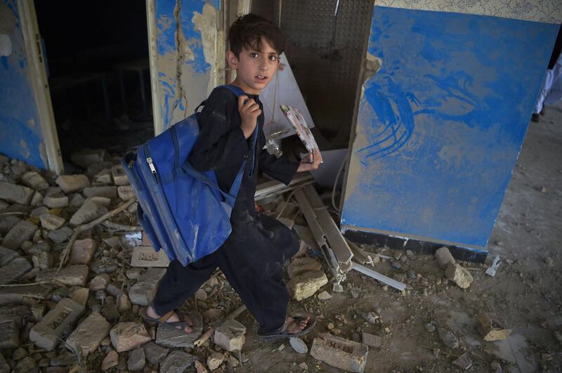 An Afghan school boy carries his backpack at a school near the site of a Taliban car bomb attack in Kabul, a day after the deadly blast at the Defence Ministry's logistics centre that also damaged nearby buildings.  AFP