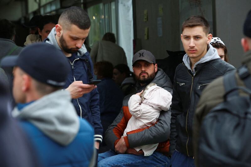 A Ukrainian man holds a baby at US-Mexican border as he waits to cross into the US. Reuters