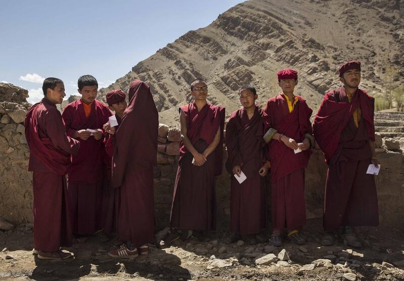 Buddhist monks from the Drukpa lineage hold their voting cards as they wait outside a polling station to vote near the Hemis Monastery.