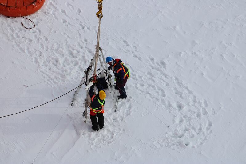 Clare Eayrs and Daiane Faller install a mast on sea ice in the Southern Ocean in 2019. The mast supports instruments to measure turbulent and radiative fluxes.