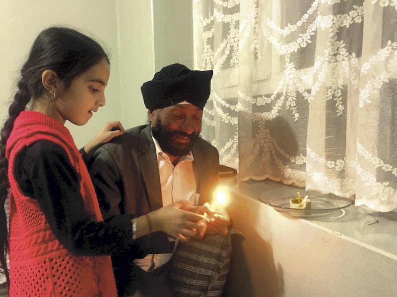 Rawail Singh helps his daughter light a lamp to mark Diwali at their home in Kabul on October 18, 2017. Ruchi Kumar