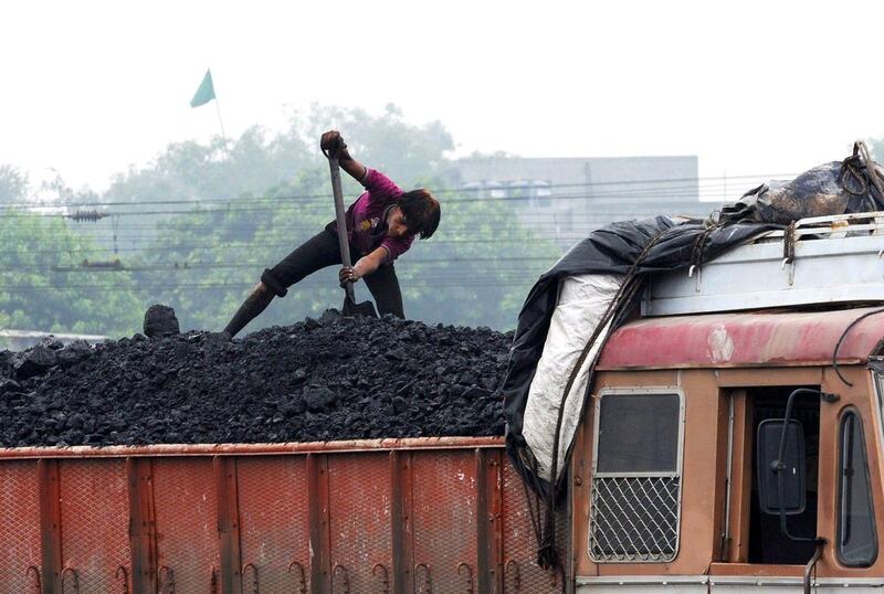 A worker loads coal onto a truck at the Kankaria Railway Yard in Ahmedabad. Sam Panthaky / AFP