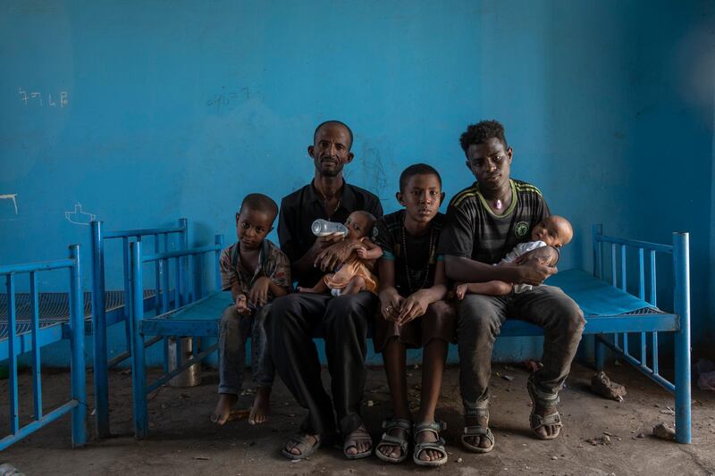 Tigrayan refugee Abraha Kinfe Gebremariam, 40, second left, sits for a photograph with his sons, Micheale, 5, left; Daniel, 11, center; his 19-year-old brother-in-law, Goytom Tsegay, second right, and his 4-month-old twin daughters Aden, right, and Turfu Gebremariam, on his lap, inside their family's shelter in Hamdayet, eastern Sudan, near the border with Ethiopia, on March 23, 2021. A fellow refugee, Mulu Gebrencheal, a mother of five, has become an informal adviser, offering guidance on the babiesâ€™ care. Abraha and his sons are quick learners, she said. But she mourns for the twins and the death of their mother. â€œEven the hug of a mother is very sweet,â€ she said. â€œTheyâ€™ve never had this. They never will.â€ (AP Photo/Nariman El-Mofty)