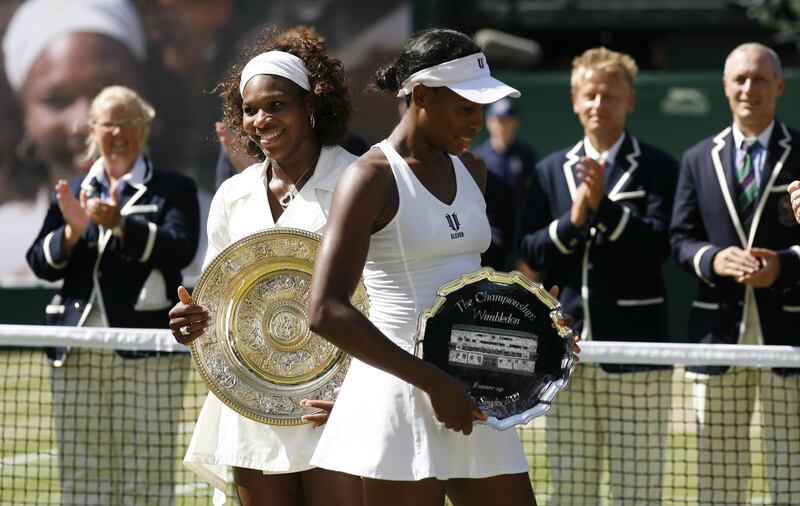 US Serena Williams (L) and US Venus Williams  hold up their trophies after their women's final match on Day 12 at the 2009 Wimbledon tennis championships at the All England Club on July 4, 2009. The event, the third Grand Slam tournament of 2009, runs from June 22  to  July  5, 2009.    Serena won 7/6,6/2.  AFP PHOTO / GLYN KIRK (Photo by GLYN KIRK / AFP)