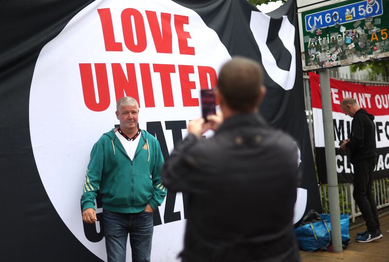 A fan has a photo taken in front of a banner protesting the Glazer family’s ownership of Manchester United. Action Images