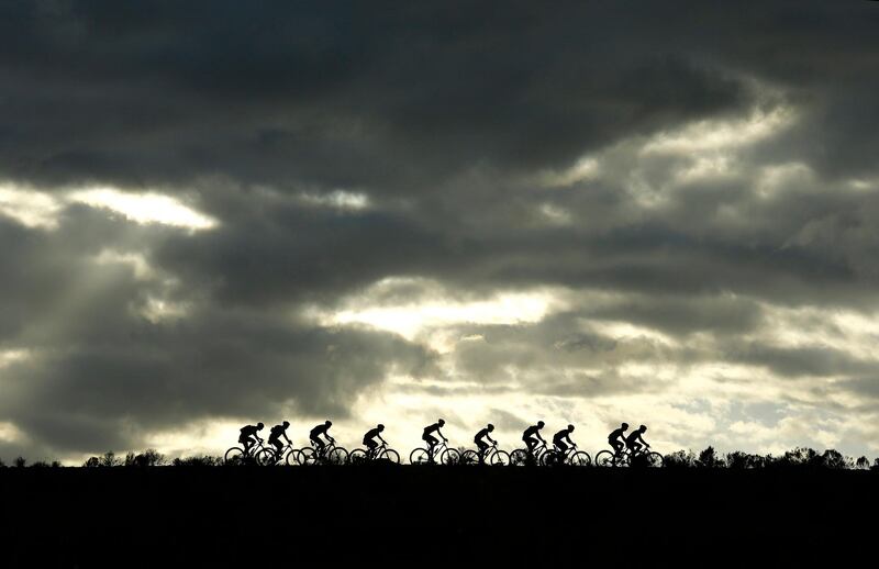 The professional peloton crosses a dam wall as the sun rises during stage 4 of the Cape Epic mountain bike race in South Africa. Kim Ludbrook / EPA