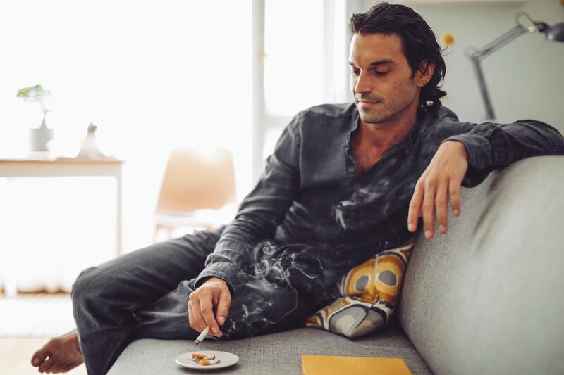 Portrait of a young man smoking indoors. Getty Images