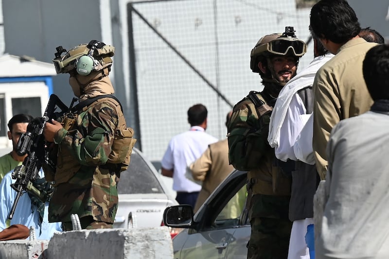 Members of the Taliban Badri 313 military unit stand guard at a check point as airport employees queue to enter to the Kabul International Airport.