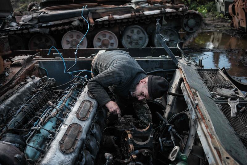 Volunteer soldier and former mechanic Gena Chiposhyn, 54, scavenges from an abandoned Russian tank near Izyum, Kharkiv region. AFP
