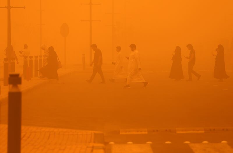 Pedestrians cross a road during the severe dust storm. AFP