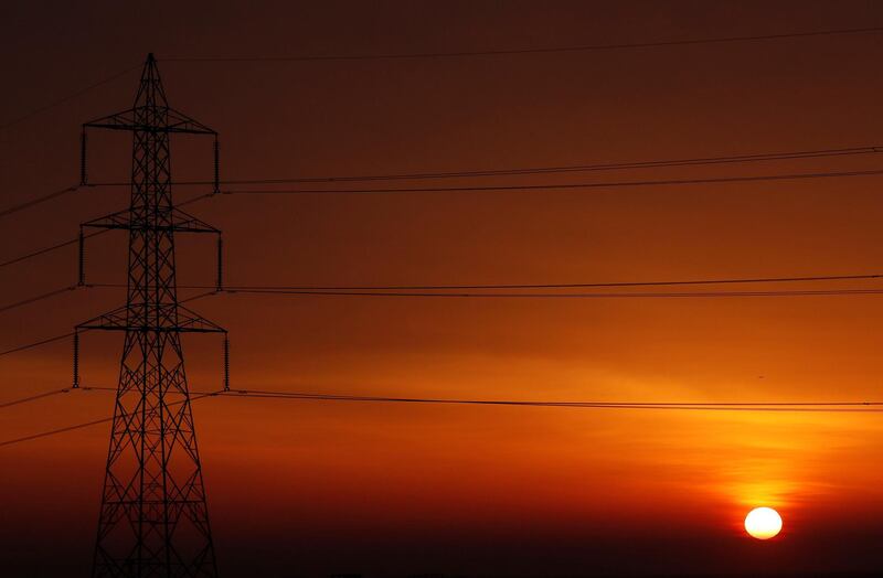 The sun is seen behind high-voltage power lines and electricity pylons at a highway northeast of Cairo, Egypt. Reuters