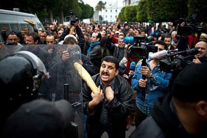A protester armed with a baguette talks to riot police during a demonstration in Tunis on January 18.