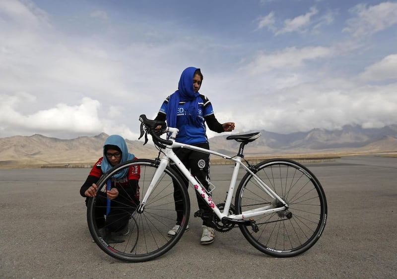 Masooma Alizada, left, and Frozan Rasooli, right, prepare a bicycle before training. Mohammad Ismail / Reuters