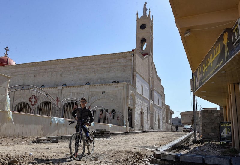 A boy stands with his bicycle by the Syriac Catholic Church of the Immaculate Conception (al-Tahira-l-Kubra), in the predominantly Christian town of Qaraqosh (Baghdeda), in Nineveh province, some 30 kilometres from Mosul on February 24, 2021, ahead of Pope Francis' March visit to Iraq. Iraq's northern province of Nineveh is the heartland of the country's Christian community and its capital, Mosul, is where the Islamic State group chose to announce the establishment of its self-styled "caliphate" in 2014. About 30 kilometres (20 miles) to the south lies Qaraqosh, also known as Baghdeda and Hamdaniya, which has a long pre-Christian history but whose residents today speak a modern dialect of Aramaic, the language of Jesus Christ. / AFP / Zaid AL-OBEIDI
