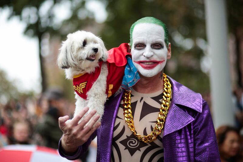A man dressed up as the Joker holds his dog in a Wonder Woman costume. AFP