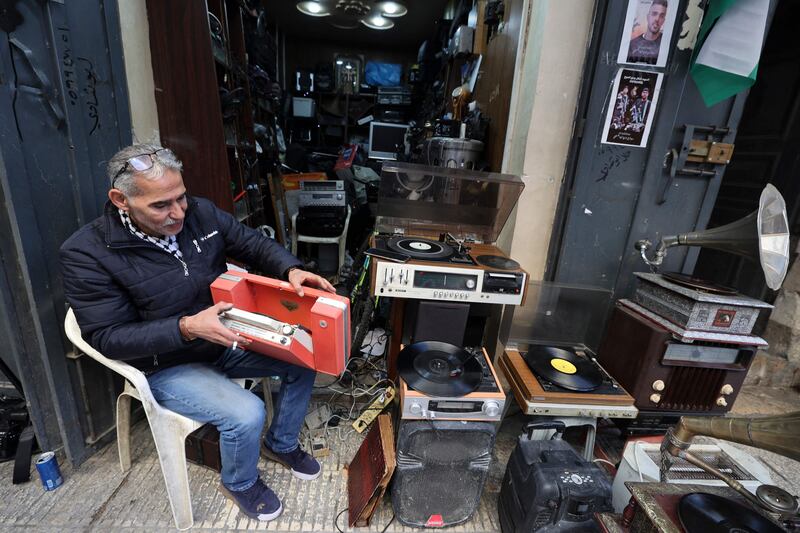 Hemmou checks a portable record player as he sits in front of his shop