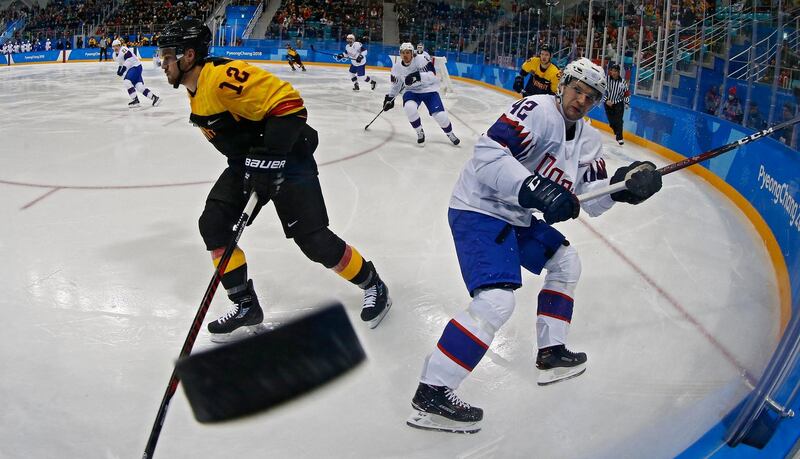 Brooks Macek (L) of Germany knocks the puck into the glass against Henrik Odegaard (R) of Norway during the men's Ice Hockey preliminary round match between Germany and Norway at the Gangneung Hockey Centre. Larry Smith / EPA